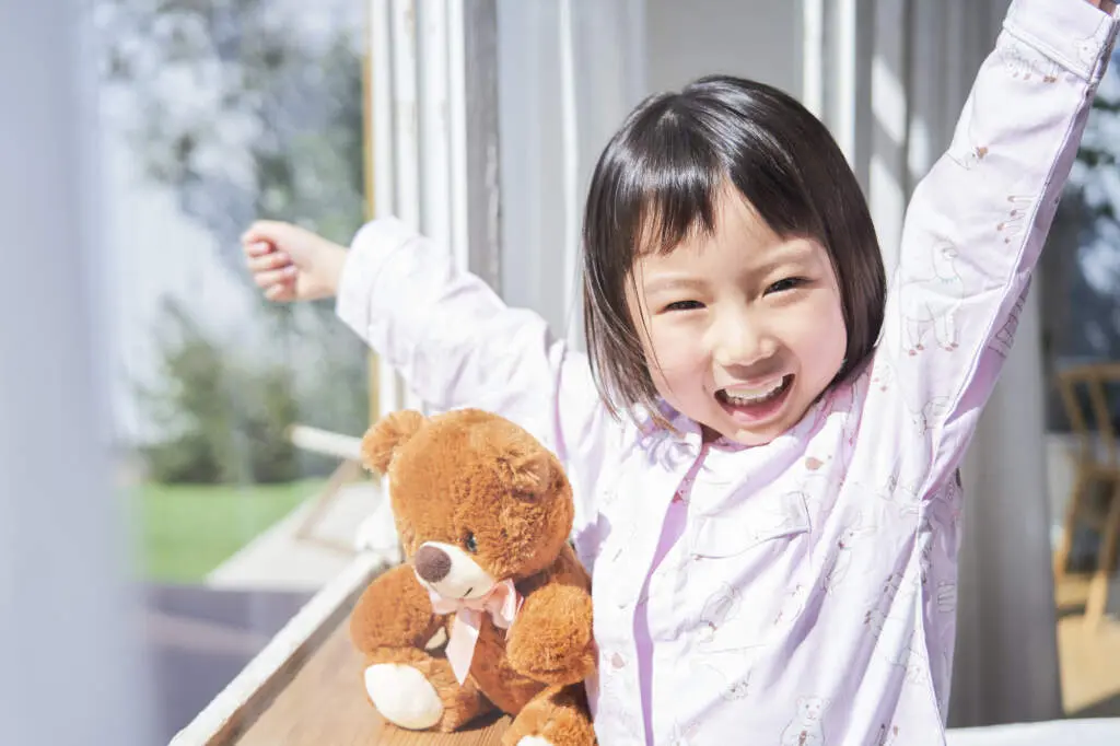 Morningroutinechildren2 | my stellaマイステラブログ|子どもの好きが育つヒントと親子の時間 朝日の中、スッキリと目覚める子どもとくまのぬいぐるみ。子どもが素敵な笑顔