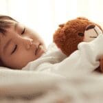 お気に入りのぬいぐるみを抱きしめて眠る子ども