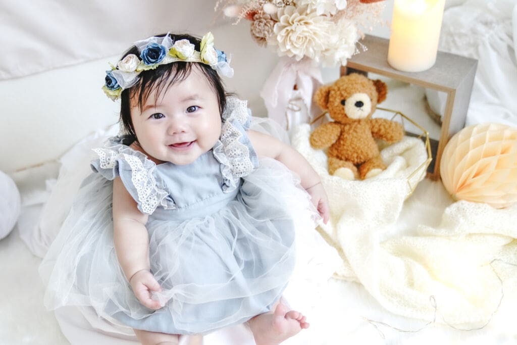 ドレスを着た1歳の女の子が、誕生日の記念に笑顔で座っている様子