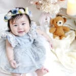 ドレスを着た1歳の女の子が、誕生日の記念に笑顔で座っている様子