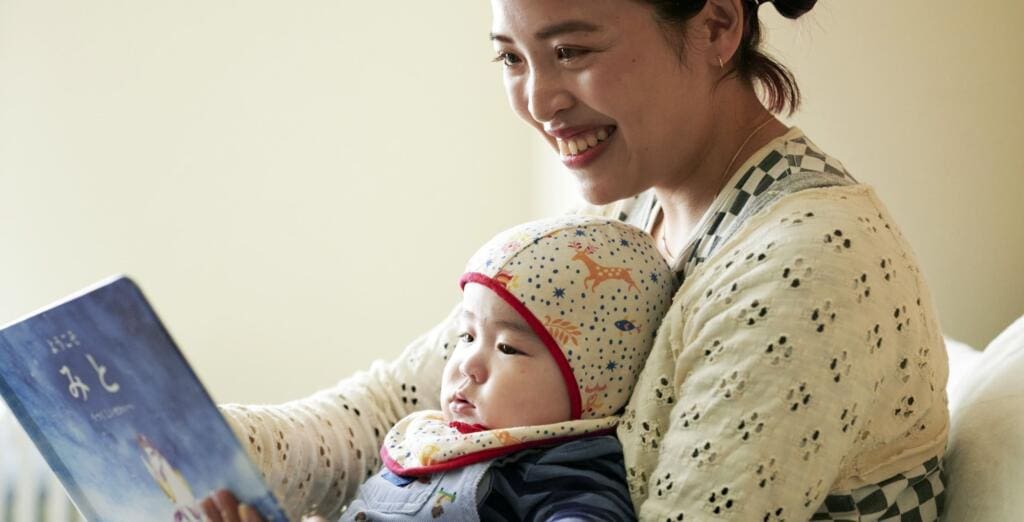母親が赤ちゃんに絵本を読み聞かせしている様子