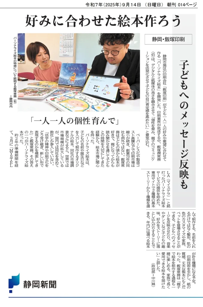 静岡新聞に掲載されたパーソナライズ絵本MY STELLAの記事。飯塚印刷の飯塚潤務がタブレットを使い絵本の特徴を説明している。見出しは「好みに合わせた絵本作ろう」「一人一人の個性育んで」