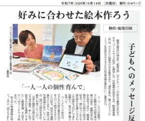 静岡新聞に掲載されたパーソナライズ絵本MY STELLAの記事。飯塚印刷の飯塚潤務がタブレットを使い絵本の特徴を説明している。見出しは「好みに合わせた絵本作ろう」「一人一人の個性育んで」